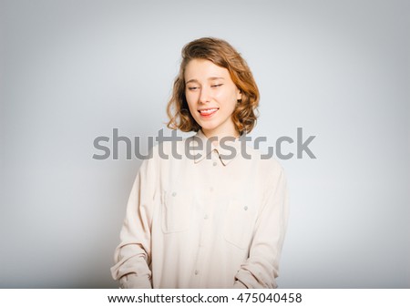beautiful happy girl showing tongue, close-up, isolated on a gray background