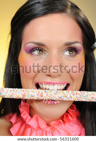 Beautiful happy girl with a sweet lollipop and creative makeup . yellow background