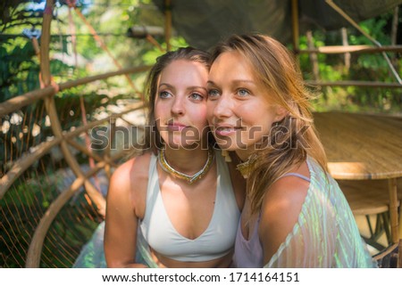 beautiful and happy girlfriends after outdoors yoga workout - two young pretty women smiling cheerful enjoying tropical jungle after fitness drill in friendship and healthy lifestyle concept