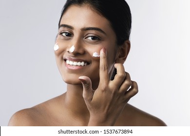 Beautiful And Happy Indian Woman Applying Moisturizing Cream On Her Face
