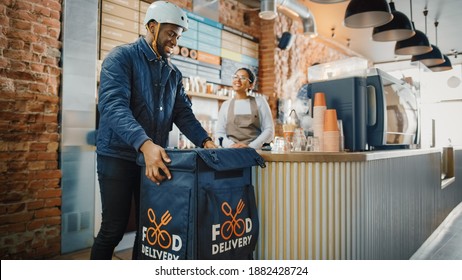 Beautiful Happy Latin Barista Serves Order of a Food Delivery Courier. Delivery Guy Puts Food in His Hot Thermal Insulated Bag and Closes it. Sunny and Bright Modern Cafe.