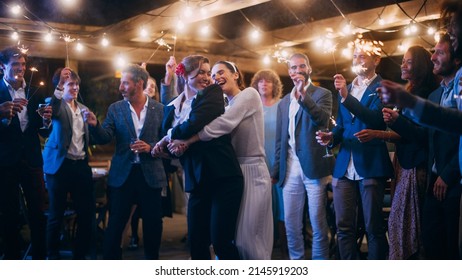 Beautiful Happy Lesbian Couple Celebrate Wedding At An Evening Reception Party With Diverse Multiethnic Friends. Queer Newlyweds Dancing At A Restaurant Venue. LGBTQ Relationship And Family Goals.