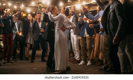 Beautiful Happy Lesbian Couple Celebrate Wedding At An Evening Reception Party With Diverse Multiethnic Friends. Queer Newlyweds Dancing At A Restaurant Venue. LGBTQ Relationship And Family Goals.