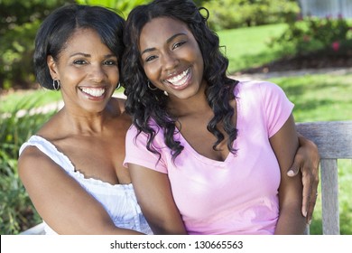 A beautiful happy middle aged African American woman mother and her daughter girl child relaxing and smiling outside together