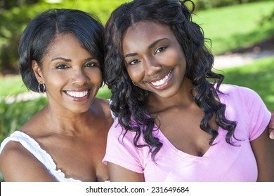 A beautiful happy middle aged African American woman mother and her daughter girl child relaxing and smiling outside together