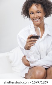 A Beautiful Happy Mixed Race African American Girl Or Young Woman Wearing A White Shirt And Drinking Red Wine At Home On A Sofa