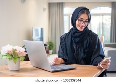 Beautiful Happy Muslim Woman Using Smart Phone And Laptop At Her Luxury Home