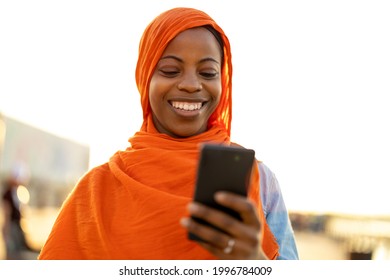 Beautiful, happy Muslim woman using smartphone outdoors
 - Powered by Shutterstock