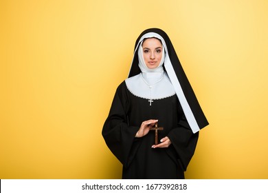 Beautiful Happy Nun Holding Cross On Yellow