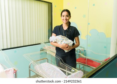 Beautiful happy nurse smiling while carrying a baby in the nursery room of the hospital  - Shutterstock ID 2149232361