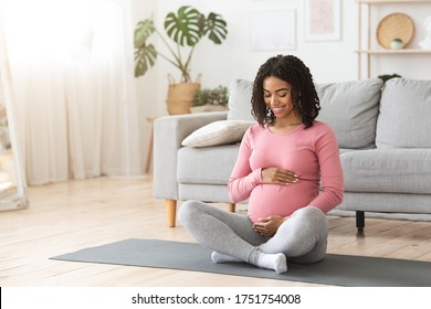 Beautiful Happy Pregnant African Woman Hugging Her Tummy, Sitting On Sport Mat, Enjoying Her Pregnancy, Free Space