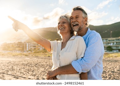 Beautiful happy senior couple dating at the seaside during summertime - Mature married couple in love bonding outdoors at the beach, concepts about elderly lifestyle, relationship and quality of life - Powered by Shutterstock