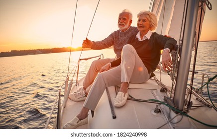 Beautiful and happy senior couple in love sitting on the side of sailboat or yacht deck floating in sea at sunset and enjoying amazing view, sailing together - Shutterstock ID 1824240998