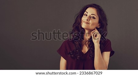 Beautiful happy smiling makeup business woman in dark red blouse with curly healthy brown hairstyle on grey background with empty copy space for text. Closeup toned vintage portrait