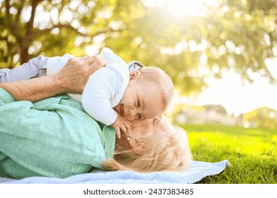 Beautiful happy smiling senior elderly woman lying on grass with cute little baby boy. Grandmother and grandson having fun time together at tropical summer day park. Multigenerational family concept - Powered by Shutterstock