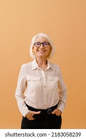 Beautiful Happy Smiling Senior Woman In Business Suit And Glasses Standing Over Isolated Brown Background