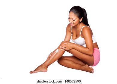Beautiful happy smiling woman applying exfoliating moisturizing lotion cream on leg, bodycare skincare concept.