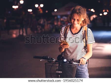 Beautiful happy smiling young woman using bike rental app in night city