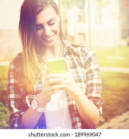 Beautiful happy teenage girl with phone texting. Caucasian brunette young woman smiling reading text message on her phone. 