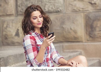 Beautiful happy teenage girl with phone texting