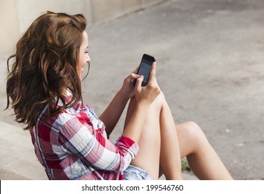 Beautiful happy teenage girl with phone texting 