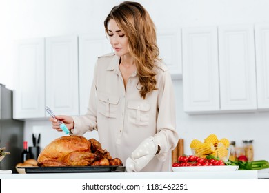 Beautiful Happy Woman Cooking Thanksgiving Turkey At Kitchen