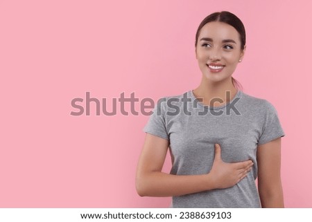 Beautiful happy woman doing breast self-examination on pink background. Space for text