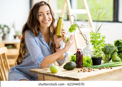 Beautiful happy woman sitting with healthy green food and drinks at home. Vegan meal and detox concept - Shutterstock ID 621944570