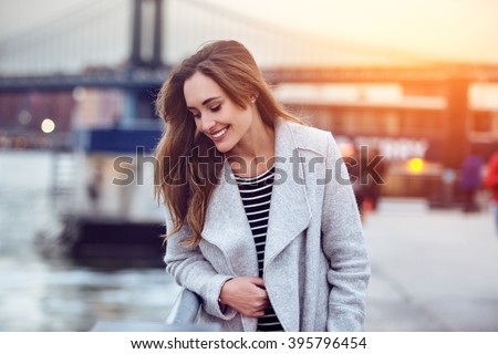 Beautiful happy woman walking near East River in New York City and looking down