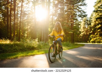 Beautiful happy woman in yellow coat riding bicycle in autumn park. Autumn fashion. Lifestyle. Relax, nature concept. - Powered by Shutterstock