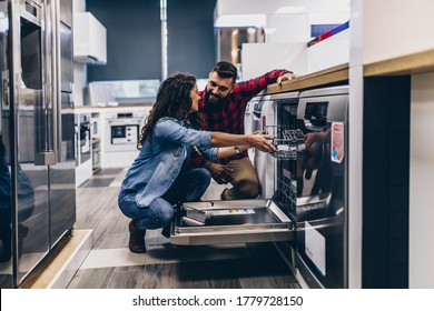 Beautiful And Happy Young Couple Buying Dishwasher In Modern Appliances Store.
