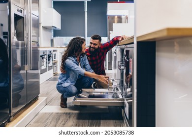 Beautiful And Happy Young Couple Buying Dishwasher In Modern Appliances Store.