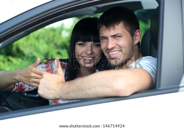 Beautiful happy young\
couple driving car