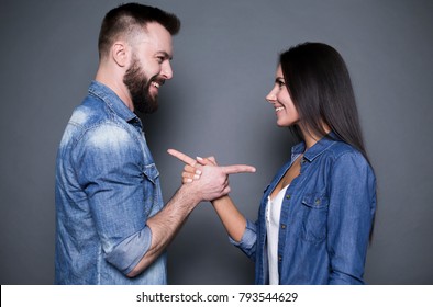Beautiful and happy young couple in love or family in casual wear having fun and making fun of each other and posing on a gray background isolated.
