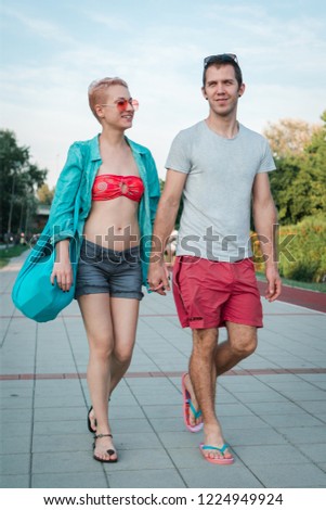 Beautiful happy young couple walking in beachwear holding hands 