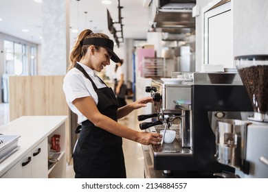 Beautiful And Happy Young Female Worker Working In A Bakery Or Fast Food Restaurant And Using Coffee Machine. Positive People In Small Business Concept.