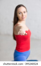 Beautiful Happy Young Woman In Bright Colorful Sportswear Working Out Indoors In Loft Interior. Girl Standing In Warrior 2 Posture, Virabhadrasana Two Pose. Close-up. Focus On The Arm. Vertical Image