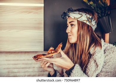 Beautiful happy young woman  eating a slice of pizza in the restaurant