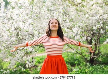 Beautiful Happy Young Woman Enjoying Smell In A Flowering Spring Garden