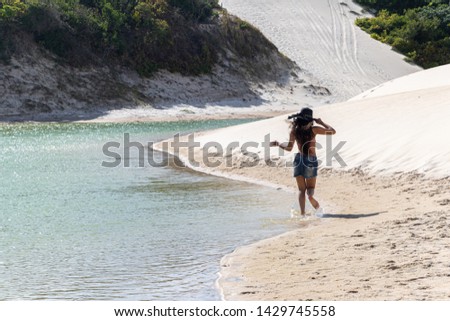 Beautiful happy young woman strolling along the dunes of the coast of Brazil. Young woman walking on the sand of the dunes.