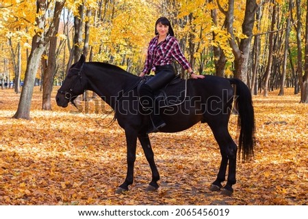 beautiful happy young woman walking with horse in autumn park