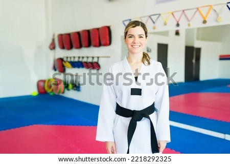 Beautiful happy young woman wearing a black bell ready to train taekwondo in a martial arts school