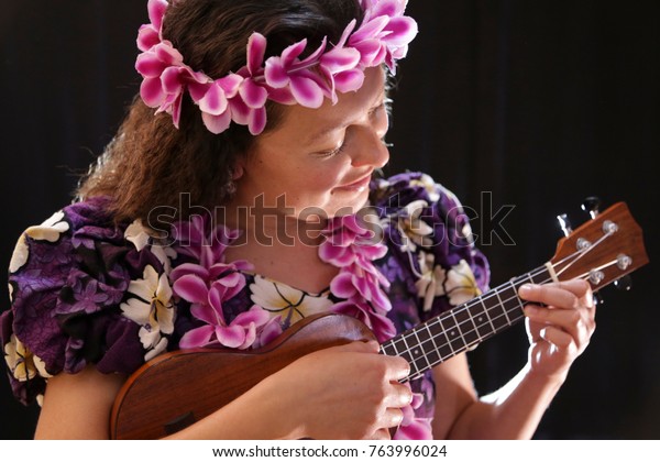 beautiful Hawaiian dancer\
with flowers and diverse outfit and playing ukulele, on black\
background