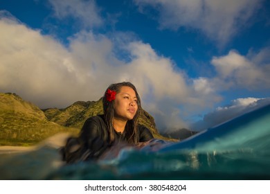 Beautiful hawaiian girl on surboard in ocean water at sunset time