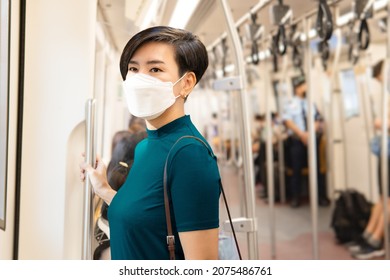 A Beautiful Healthy Asian Working Woman In Teal Green Smart Casual Top With Face Mask Standing In A City Skytrain She Look Out The Window. Urban, New Normal, Lifestyle, Covid 19, Insurance, Vaccinated