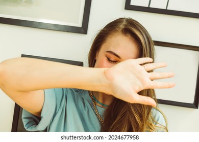 Beautiful Healthy Female Woman, With Picture Frames In Background - Camera Shy, Covering Her Face, Stop, Hand In Front Of Camera