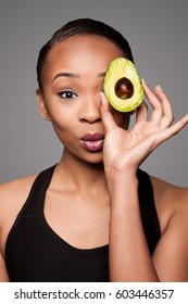 Beautiful Healthy Happy Black Asian Woman Holding Delicious Avocado Super Fruit In Front Of Eye.