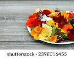 Beautiful healthy vegan salad of lettuce and colourful edible  flowers (nasturtium, calendula and pansy) on the wooden garden table.