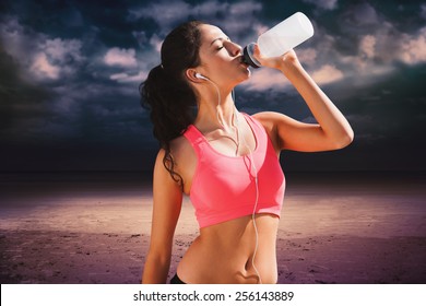 Beautiful healthy woman drinking water against dark cloudy sky - Powered by Shutterstock