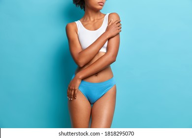 Beautiful Healthy Woman With Perfect Figure Dressed In Underwear Poses Bare Shoulders Has Slender Legs Isolated On Blue Background. Natural Beauty Concept